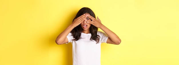 Foto gratuita retrato de niña afroamericana avergonzada y conmocionada cerró los ojos pero mirando a través de los dedos un