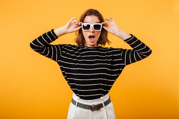 Retrato de una niña alegre en gafas de sol posando