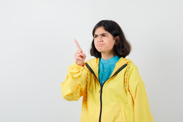 Retrato de niña apuntando hacia afuera en camisa, chaqueta y mirando pensativo vista frontal