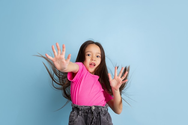 Foto gratuita retrato de niña asombrada en estudio azul