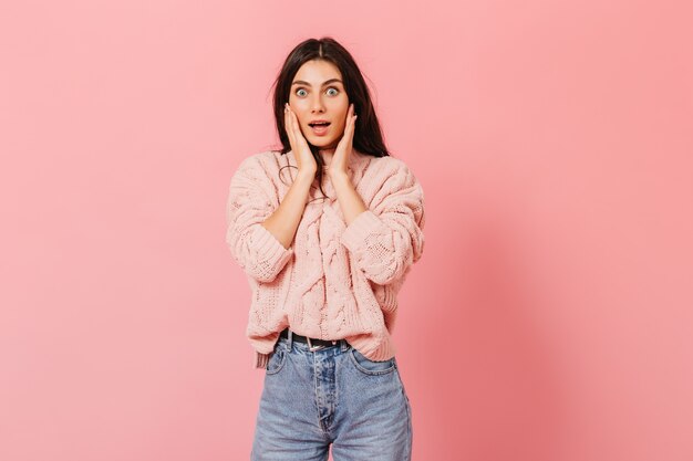 Retrato de niña asombrada en jeans y suéter rosa. Señora en estado de shock mirando a la cámara.