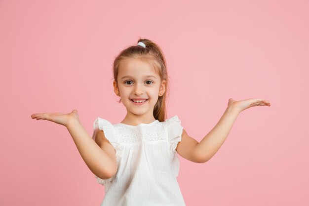 Retrato de niña bastante caucásica aislado sobre fondo de estudio rosa con copyspace