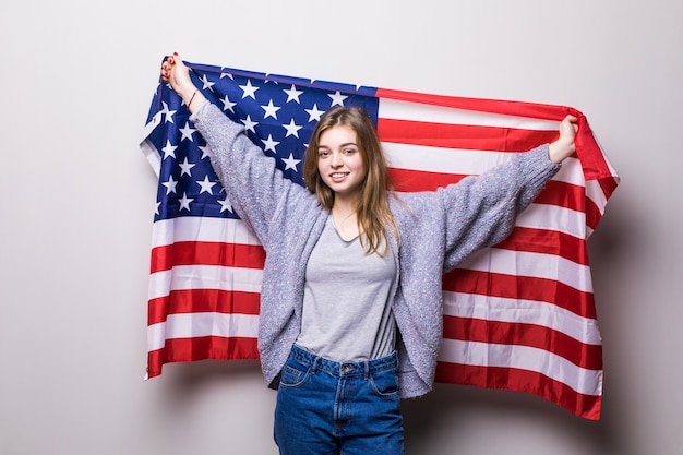 Retrato de niña bonita adolescente sosteniendo la bandera de Estados Unidos aislado en gris. Celebración del 4 de julio.
