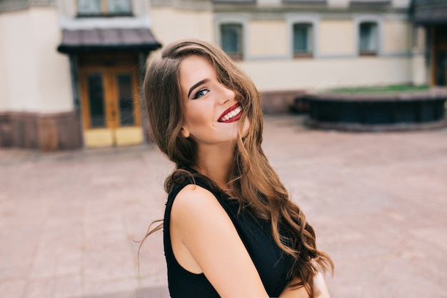 Retrato de niña bonita con pelo largo y rizado posando en la calle