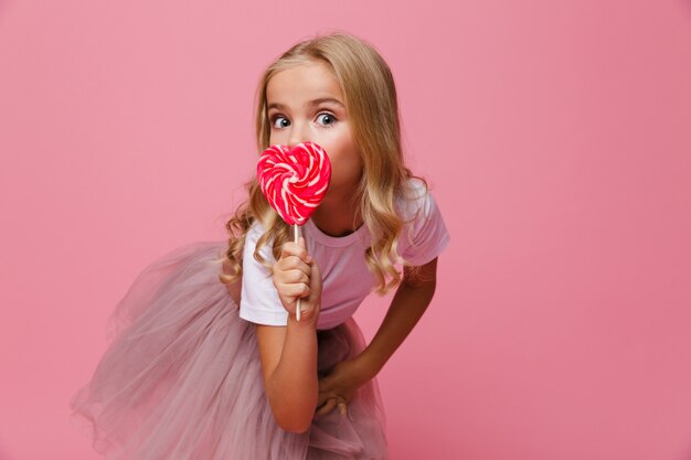 Retrato de una niña bonita con piruleta en forma de corazón