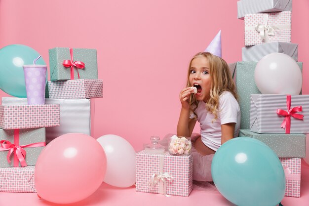 Retrato de una niña bonita en un sombrero de cumpleaños celebrando