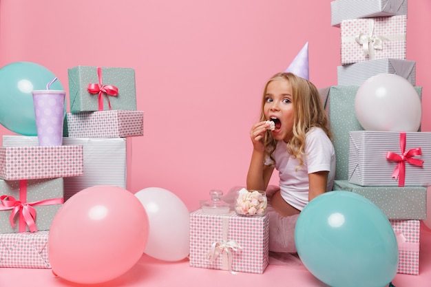 Retrato de una niña bonita en un sombrero de cumpleaños celebrando