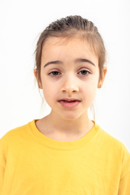 Retrato de una niña con una camiseta amarilla aislada sobre un fondo blanco
