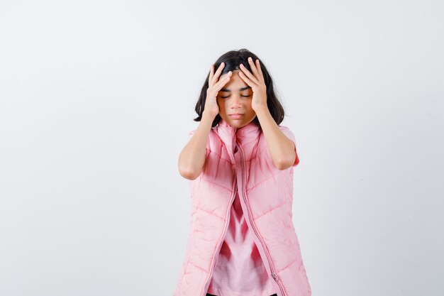 Retrato de una niña en camiseta blanca y chaleco acolchado mirando agotado