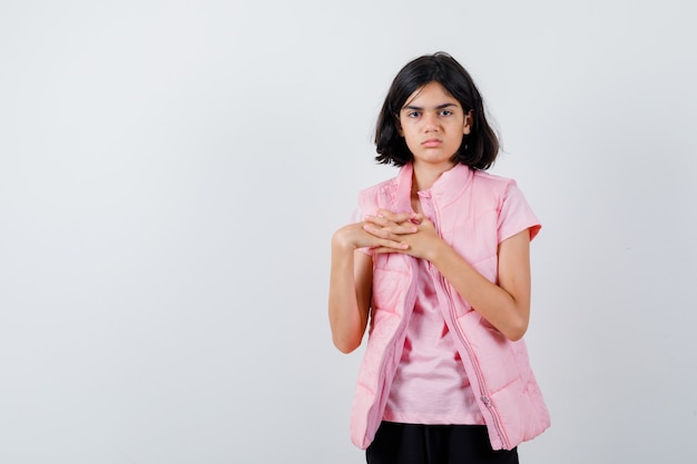 Retrato de una niña en camiseta blanca y chaleco acolchado