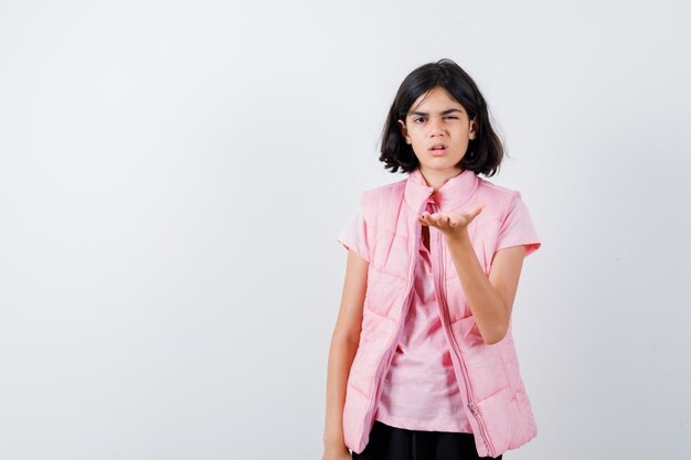 Retrato de una niña en camiseta blanca y chaleco acolchado