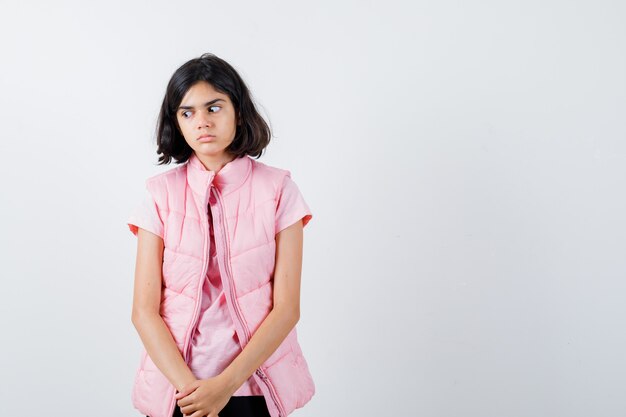 Retrato de una niña en camiseta blanca y chaleco acolchado