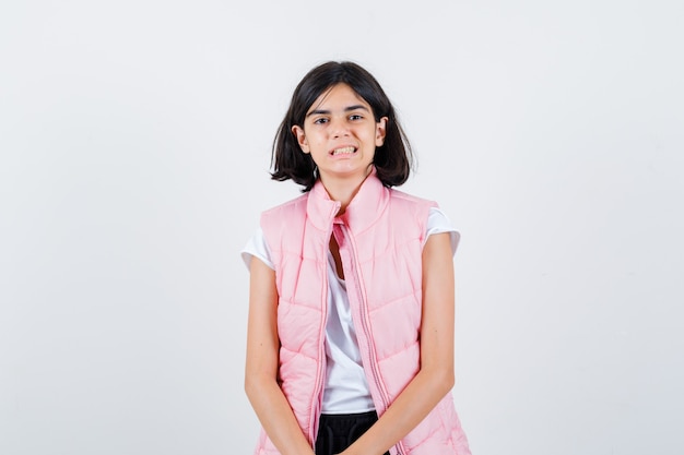 Retrato de una niña en camiseta blanca y chaleco acolchado