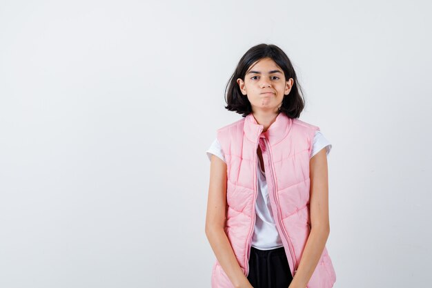 Retrato de una niña en camiseta blanca y chaleco acolchado