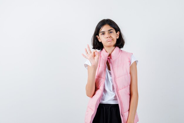 Retrato de una niña en camiseta blanca y chaleco acolchado