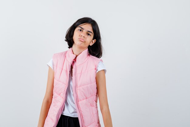 Retrato de una niña en camiseta blanca y chaleco acolchado