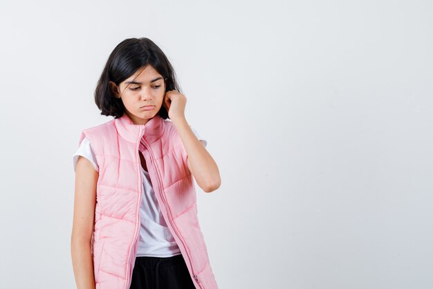 Retrato de una niña en camiseta blanca y chaleco acolchado