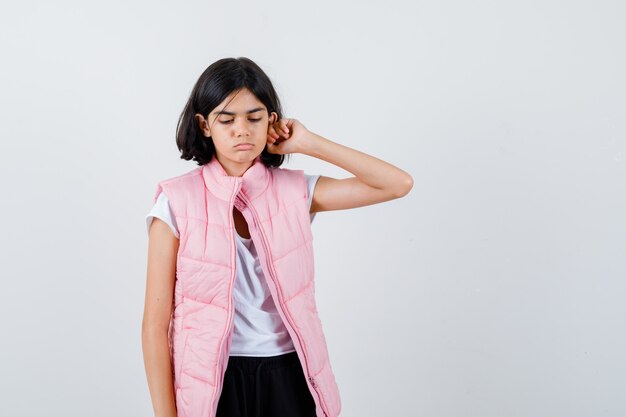 Retrato de una niña en camiseta blanca y chaleco acolchado