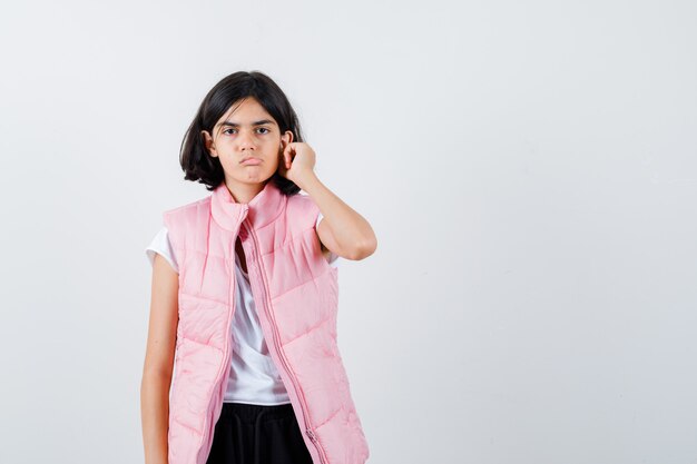 Retrato de una niña en camiseta blanca y chaleco acolchado