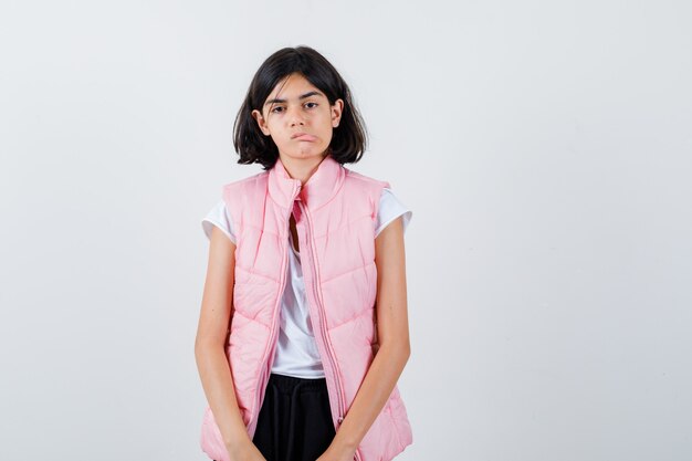 Retrato de una niña en camiseta blanca y chaleco acolchado