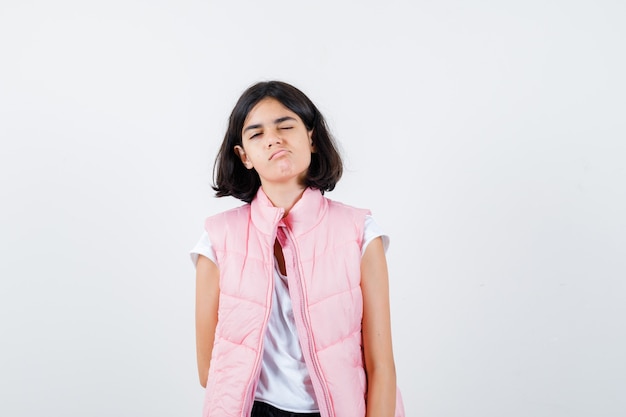 Retrato de una niña en camiseta blanca y chaleco acolchado