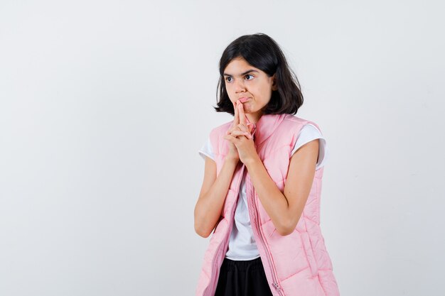 Retrato de una niña en camiseta blanca y chaleco acolchado