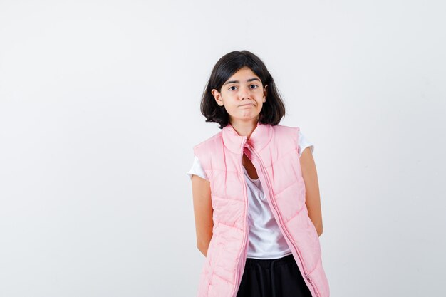 Retrato de una niña en camiseta blanca y chaleco acolchado