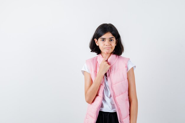 Retrato de una niña en camiseta blanca y chaleco acolchado