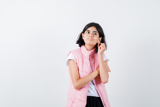 Retrato de una niña en camiseta blanca y chaleco acolchado