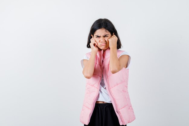 Retrato de una niña en camiseta blanca y chaleco acolchado