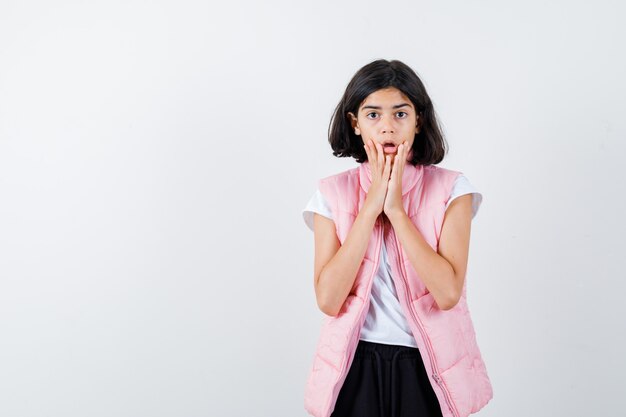 Retrato de una niña en camiseta blanca y chaleco acolchado