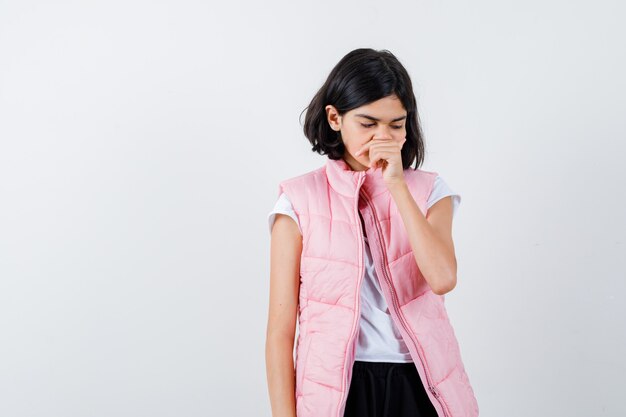Retrato de una niña en camiseta blanca y chaleco hinchable que cubre la boca