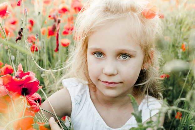 Retrato de una niña entre el campo de amapolas