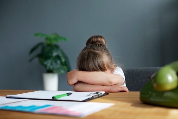 Retrato de niña cansada en su escritorio de oficina