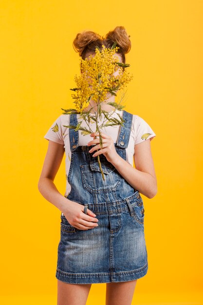 Retrato niña cara cubierta con ramas de flores