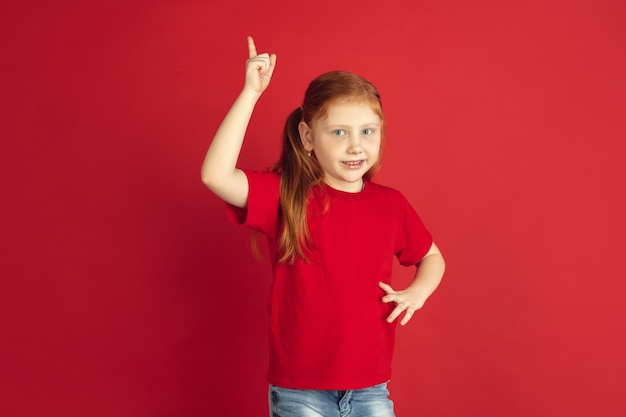 Retrato de niña caucásica aislado en la pared roja