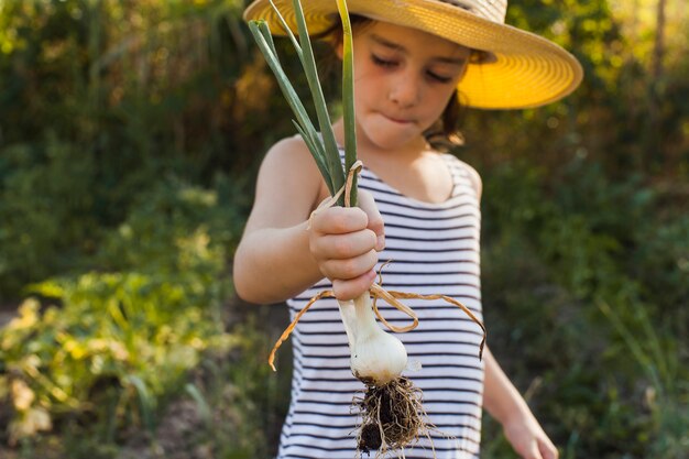 Retrato de niña con cebolla de primavera cosechada