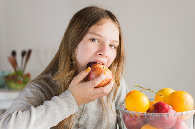 Foto gratuita retrato de una niña comiendo manzana roja