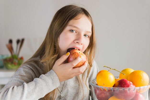 Retrato de una niña comiendo manzana roja