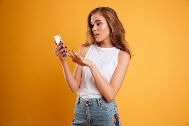 Retrato de una niña confundida frustrada mirando el teléfono móvil