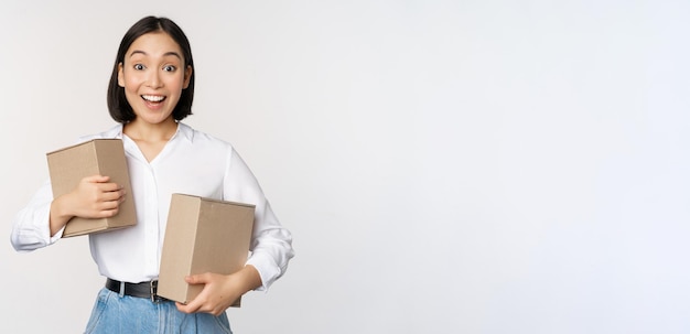 Retrato de niña coreana feliz sosteniendo dos cajas y sonriendo mirando asombrado por el concepto de cámara de fondo blanco de compras