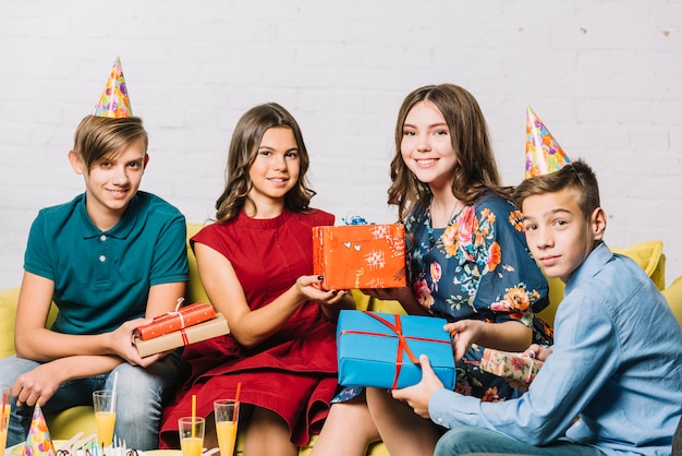 Retrato de niña de cumpleaños con sus amigos con regalos en mano