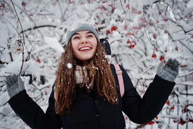 Retrato de niña en el día de nieve de invierno cerca de árboles cubiertos de nieve