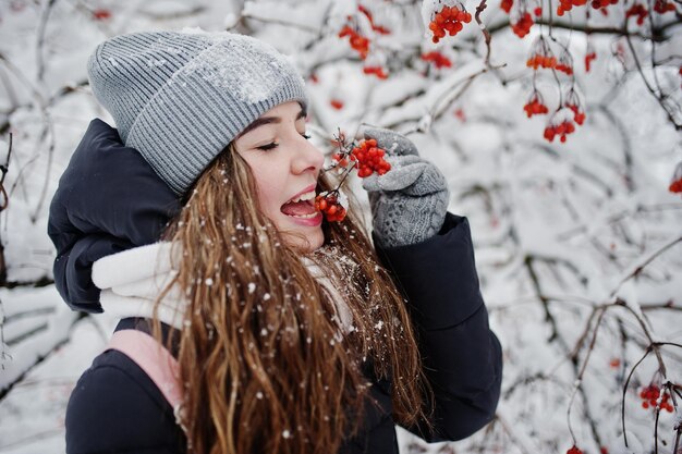 Retrato de niña en el día de nieve de invierno cerca de árboles cubiertos de nieve