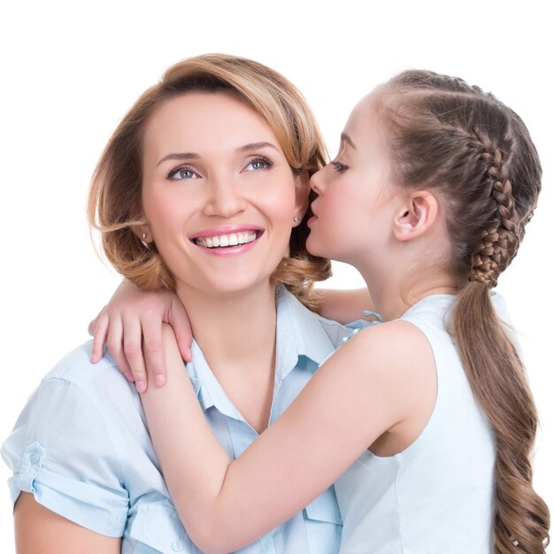 Retrato de una niña diciéndole a su madre una foto de estudio secreta