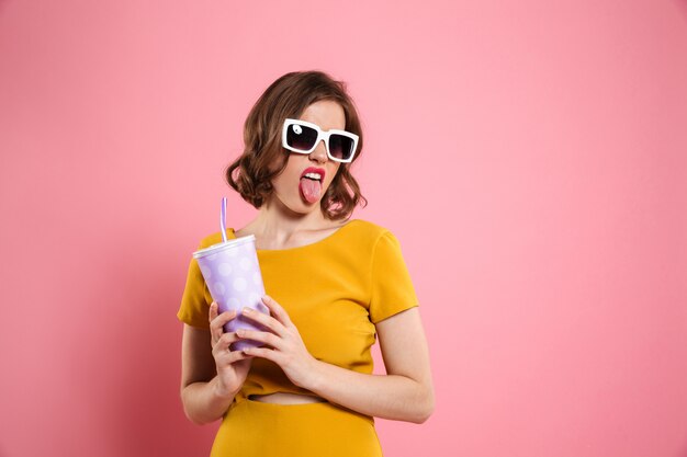 Retrato de una niña divertida en gafas de sol con taza