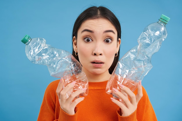 Foto gratuita retrato de niña con dos botellas de plástico parece confundido trató de reciclar clasificación de basura aislado o