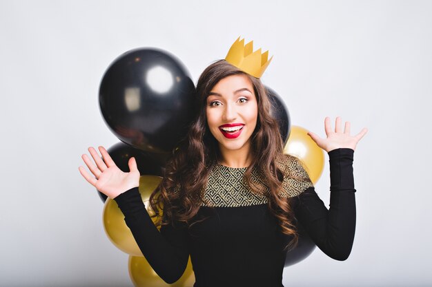 Retrato niña emocionada divertida celebrando el año nuevo con globos dorados y negros