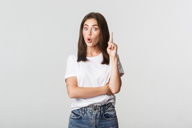 Retrato de niña emocionada levantando el dedo, tiene sugerencia o pensamiento