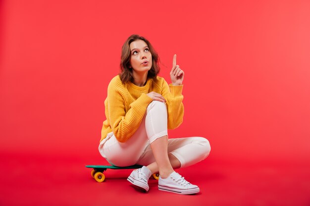 Retrato de una niña excitada sentada en una patineta